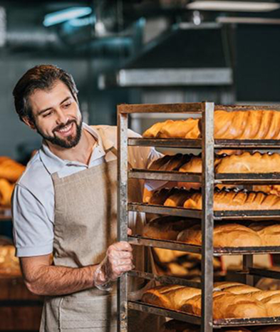 smiling baker holding a tray of bread
